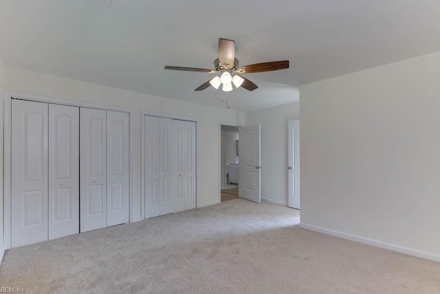 unfurnished bedroom with multiple closets, light carpet, and ceiling fan