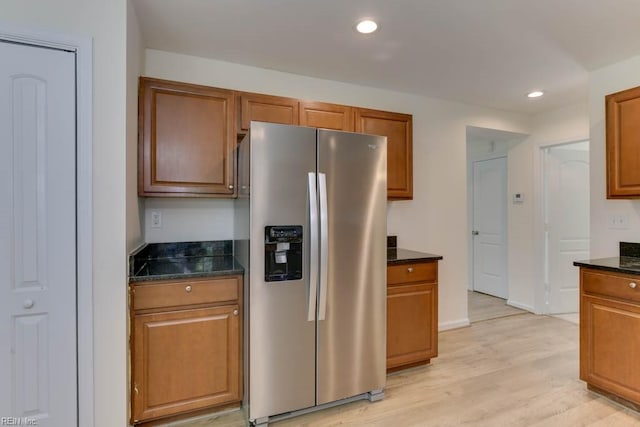 kitchen featuring stainless steel fridge, dark stone countertops, and light hardwood / wood-style flooring