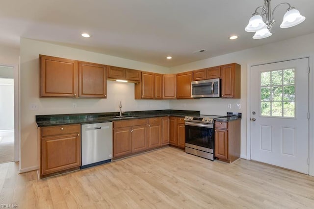 kitchen with stainless steel appliances, light hardwood / wood-style floors, sink, decorative light fixtures, and a chandelier