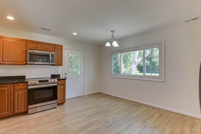 kitchen with light wood-type flooring, pendant lighting, an inviting chandelier, and stainless steel appliances