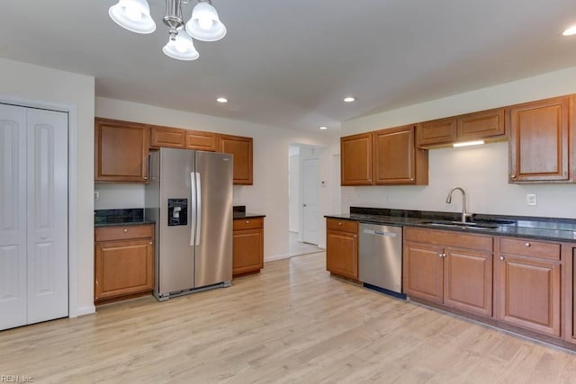 kitchen featuring stainless steel appliances, light wood-type flooring, a notable chandelier, hanging light fixtures, and sink