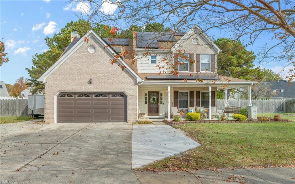 view of front of property featuring solar panels, a porch, a front yard, and a garage