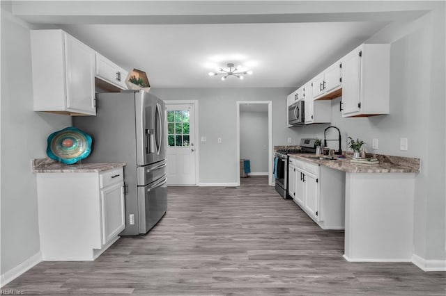 kitchen featuring sink, appliances with stainless steel finishes, light stone countertops, white cabinets, and light wood-type flooring