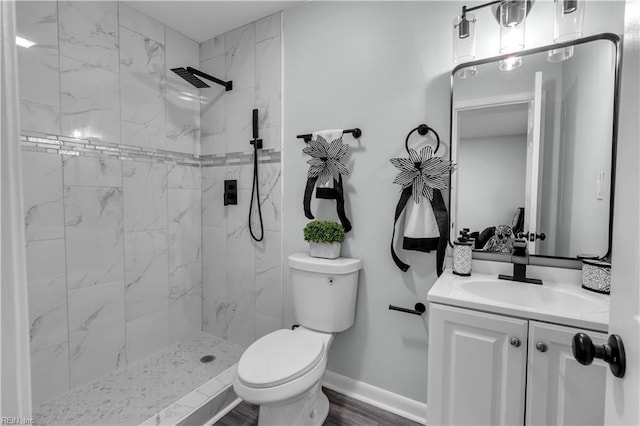 bathroom with toilet, vanity, wood-type flooring, and a tile shower