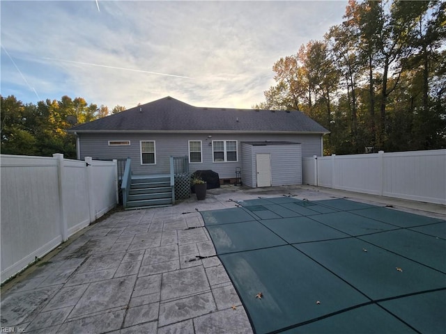 back of property featuring a covered pool and a patio