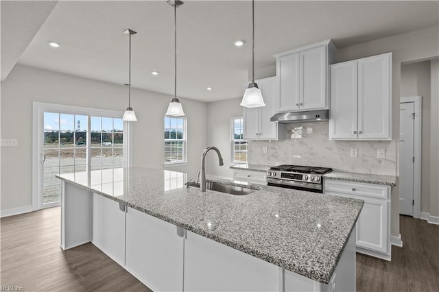 kitchen featuring high end stove, white cabinetry, a healthy amount of sunlight, and sink