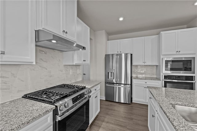 kitchen featuring backsplash, white cabinets, dark hardwood / wood-style floors, light stone countertops, and stainless steel appliances