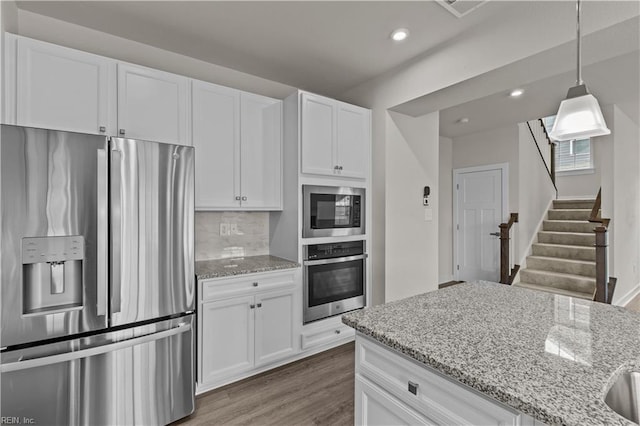 kitchen with dark hardwood / wood-style floors, decorative backsplash, white cabinetry, and appliances with stainless steel finishes