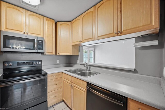 kitchen with light brown cabinetry, sink, light tile patterned floors, and stainless steel appliances