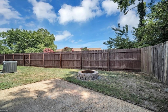 view of yard with central AC unit, a patio area, and an outdoor fire pit