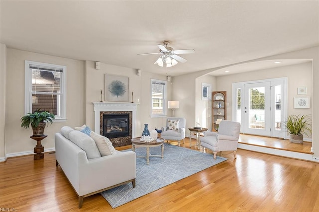 living room featuring wood-type flooring, ceiling fan, and a fireplace