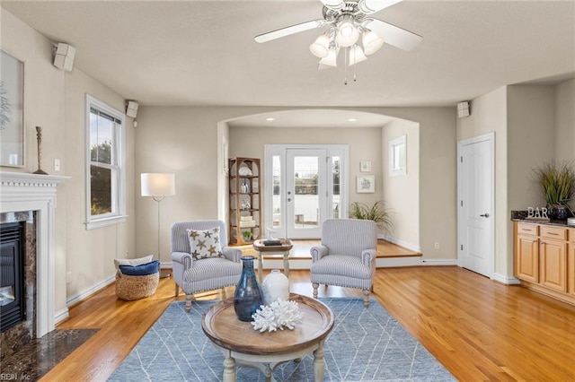 living room featuring ceiling fan, plenty of natural light, light wood-type flooring, and a fireplace