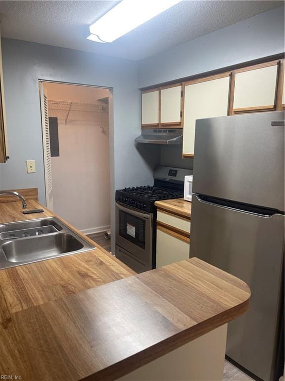 kitchen with white cabinets, appliances with stainless steel finishes, a textured ceiling, and sink