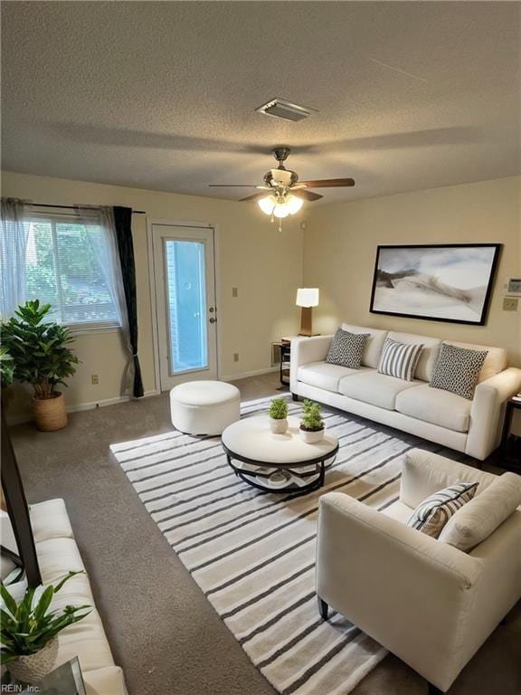 carpeted living room with a textured ceiling and ceiling fan