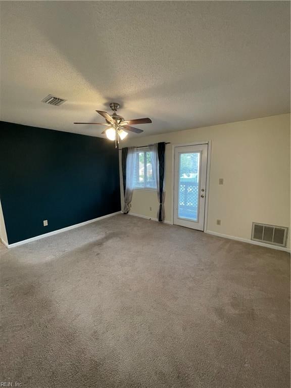 carpeted spare room featuring ceiling fan and a textured ceiling