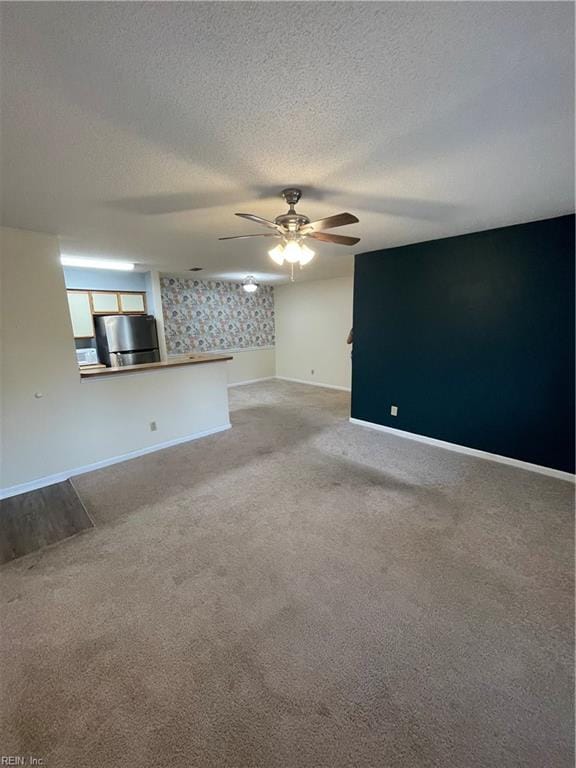 carpeted empty room featuring ceiling fan and a textured ceiling