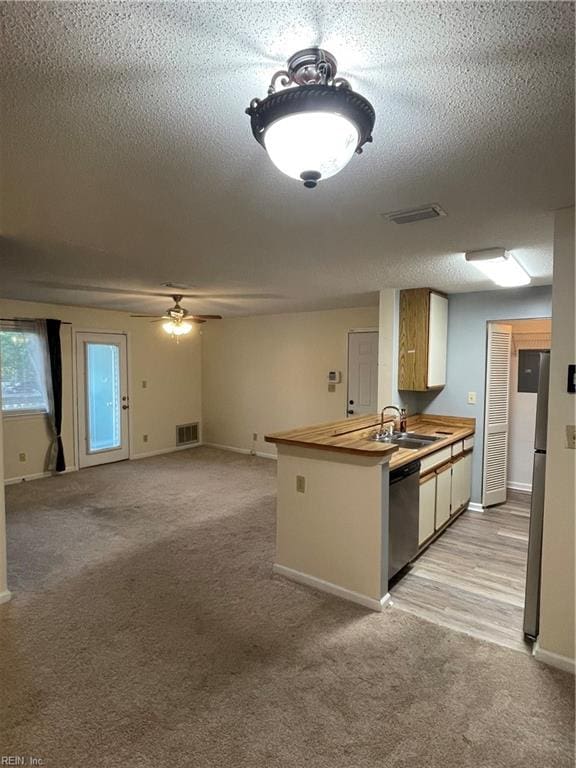 kitchen with sink, appliances with stainless steel finishes, wooden counters, ceiling fan, and a textured ceiling