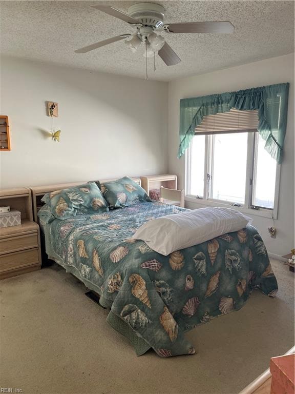 bedroom with a textured ceiling, carpet flooring, and ceiling fan