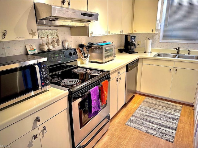 kitchen with light wood-type flooring, appliances with stainless steel finishes, and sink