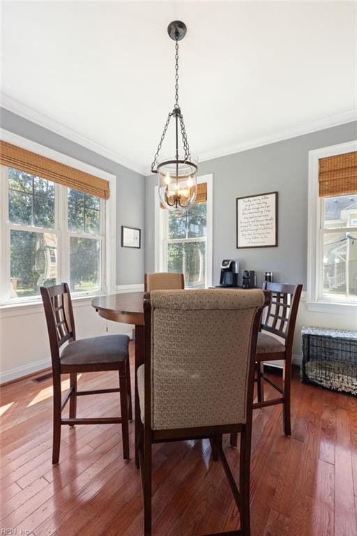 dining area featuring hardwood / wood-style flooring, baseboards, a chandelier, and crown molding