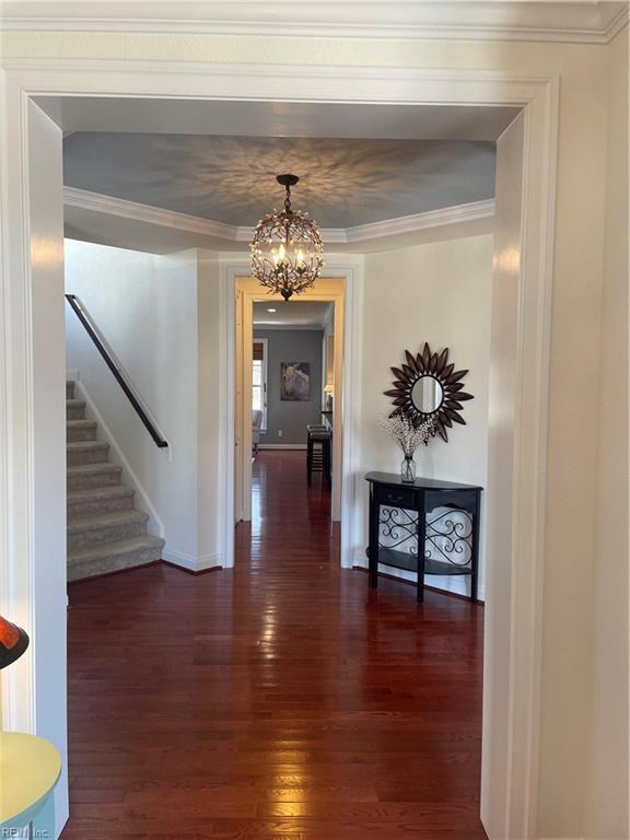 hall featuring dark wood-style floors, stairway, baseboards, and crown molding