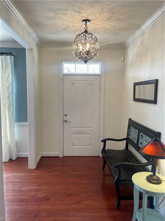 foyer featuring ornamental molding, a chandelier, dark wood finished floors, and baseboards