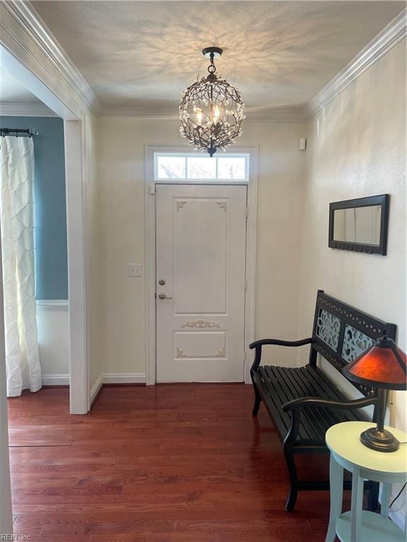 foyer featuring ornamental molding, dark wood-style flooring, baseboards, and an inviting chandelier