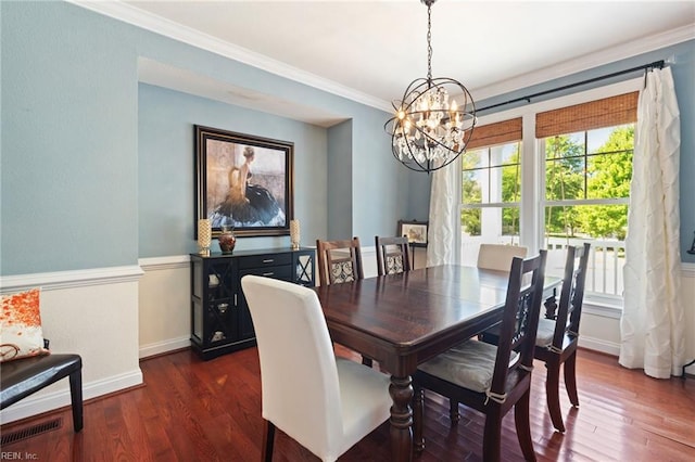 dining room featuring ornamental molding, dark wood-type flooring, baseboards, and an inviting chandelier