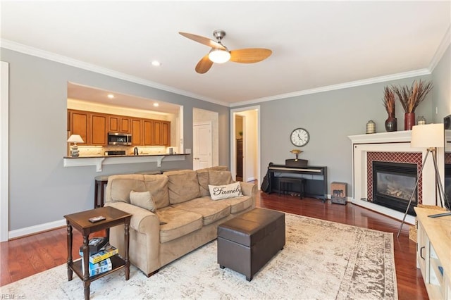 living area with crown molding, a fireplace, light wood-style flooring, and baseboards