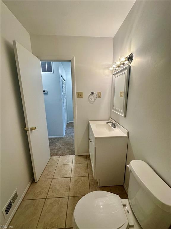 bathroom with toilet, vanity, and tile patterned floors