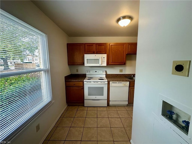 kitchen with white appliances, sink, and light tile patterned floors