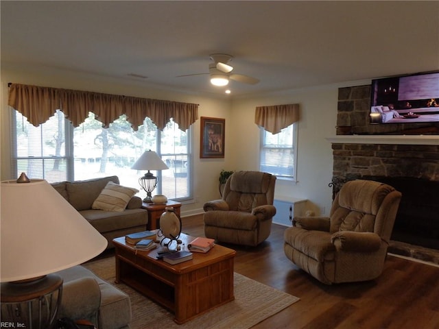 living room featuring ceiling fan, wood-type flooring, a healthy amount of sunlight, and a stone fireplace