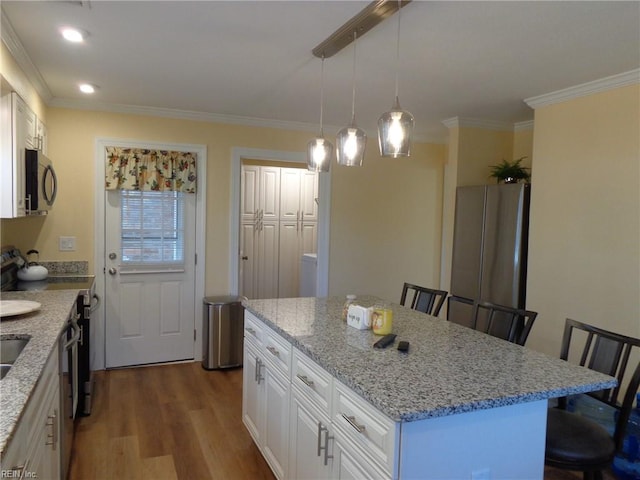 kitchen featuring a center island, hardwood / wood-style flooring, a breakfast bar, and white cabinets