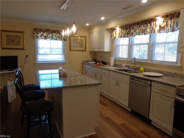 kitchen with hardwood / wood-style flooring, sink, appliances with stainless steel finishes, a center island, and white cabinets