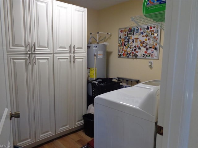 laundry area featuring hardwood / wood-style floors, cabinets, water heater, and separate washer and dryer