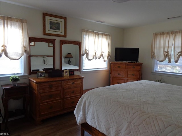 bedroom with dark hardwood / wood-style floors and multiple windows