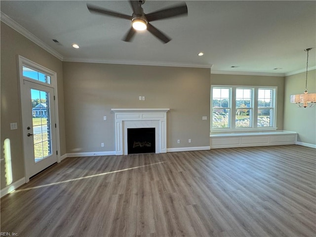 unfurnished living room featuring ceiling fan with notable chandelier, hardwood / wood-style flooring, and crown molding