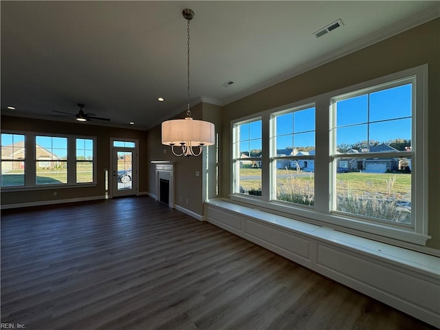 unfurnished living room featuring dark wood-type flooring, ornamental molding, ceiling fan, and a healthy amount of sunlight