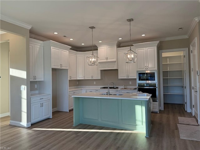 kitchen featuring pendant lighting, appliances with stainless steel finishes, a kitchen island with sink, and white cabinets