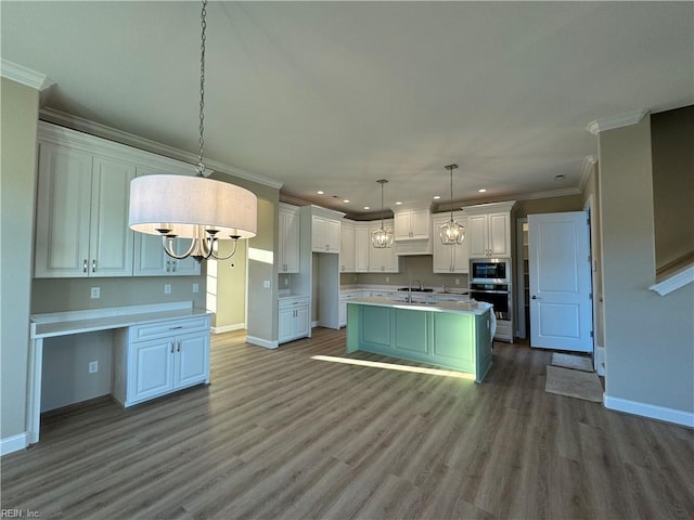 kitchen featuring pendant lighting, hardwood / wood-style floors, an island with sink, white cabinetry, and appliances with stainless steel finishes