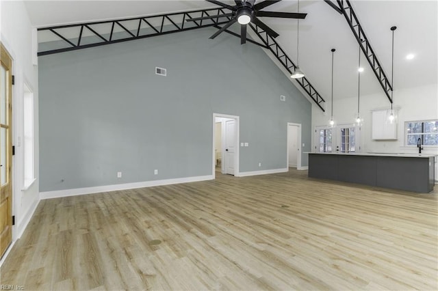 unfurnished living room featuring high vaulted ceiling, light hardwood / wood-style floors, and ceiling fan