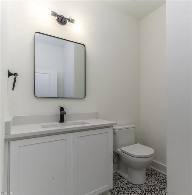 bathroom with toilet, vanity, and tile patterned floors