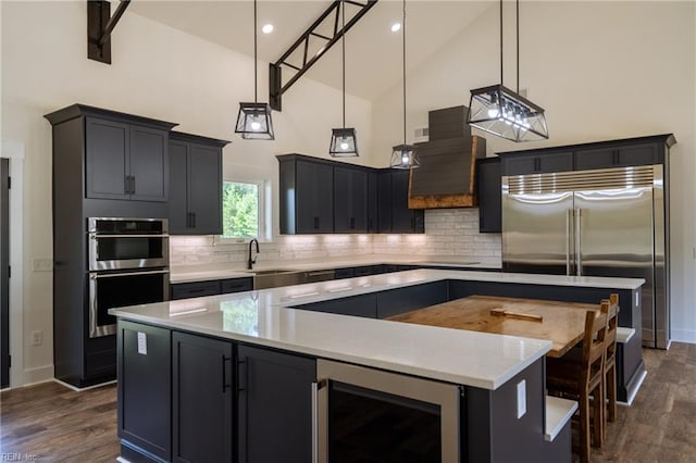 kitchen with a kitchen island, decorative light fixtures, dark hardwood / wood-style floors, high vaulted ceiling, and beverage cooler