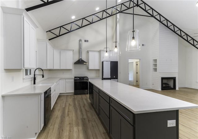 kitchen featuring white cabinetry, black appliances, hanging light fixtures, a towering ceiling, and a center island