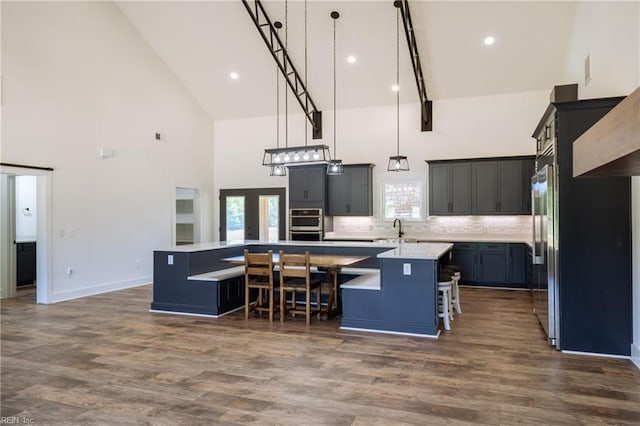 kitchen featuring a kitchen bar, high vaulted ceiling, dark hardwood / wood-style flooring, hanging light fixtures, and a center island