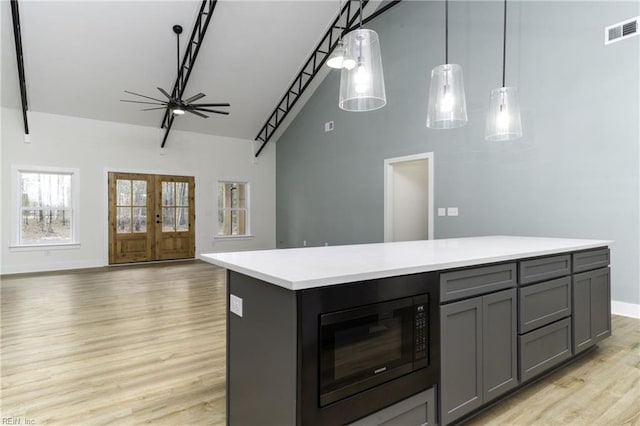 kitchen featuring gray cabinetry, pendant lighting, light hardwood / wood-style floors, black microwave, and a center island