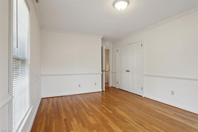 empty room with hardwood / wood-style flooring and crown molding