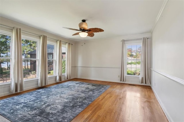 unfurnished room featuring hardwood / wood-style flooring, a healthy amount of sunlight, crown molding, and ceiling fan