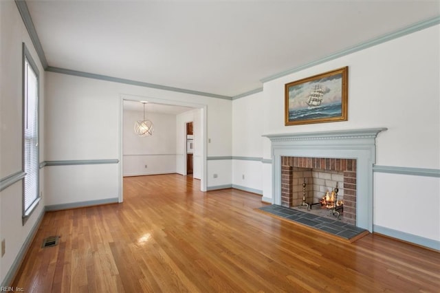 unfurnished living room featuring ornamental molding, hardwood / wood-style flooring, a healthy amount of sunlight, and a fireplace