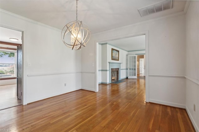 unfurnished dining area with hardwood / wood-style floors, crown molding, and an inviting chandelier